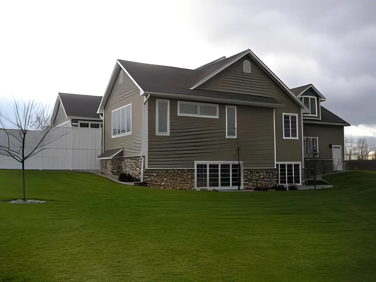 A grey house with a green lawn and overcast sky.