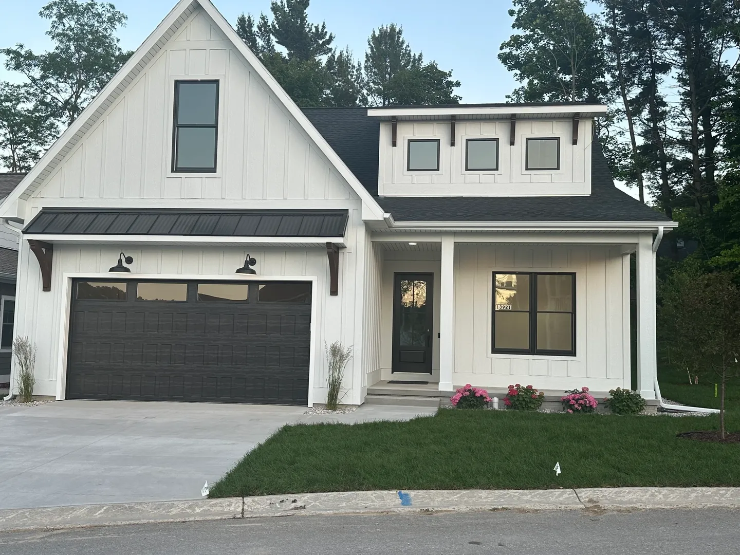 Modern white house with black trim and a manicured lawn.